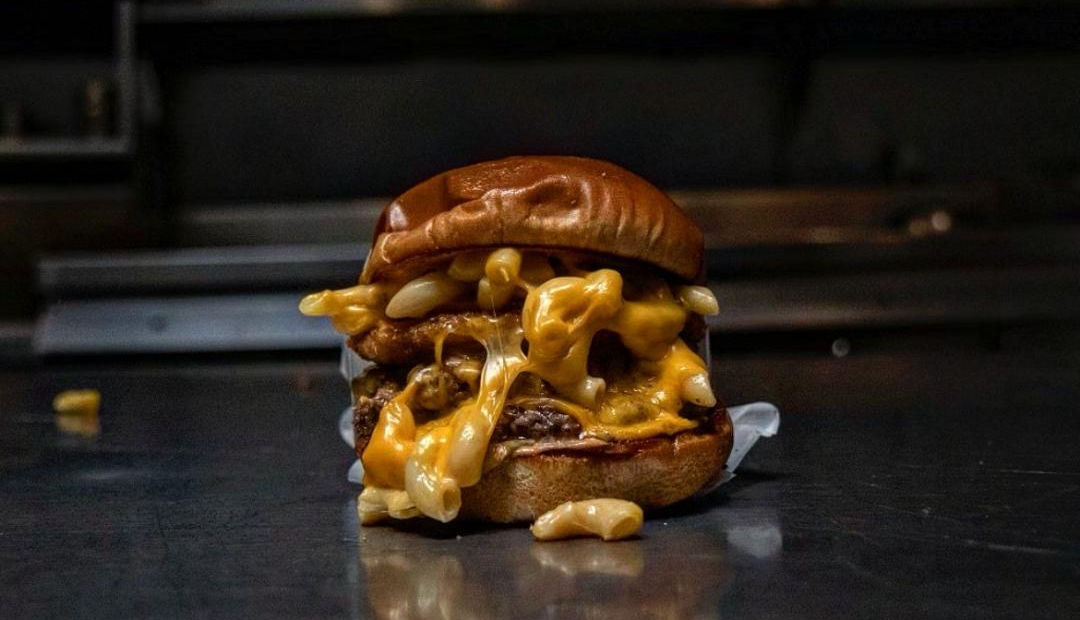 Urban Skillet burger with cheese, mac and cheese, and onion rings
